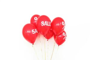 Vibrant red balloons displaying sale text and percentage signs, ideal for promotions.